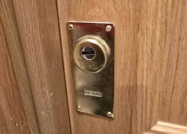 Bombín de latón instalado en el escudo de una puerta de madera, visto de cerca.