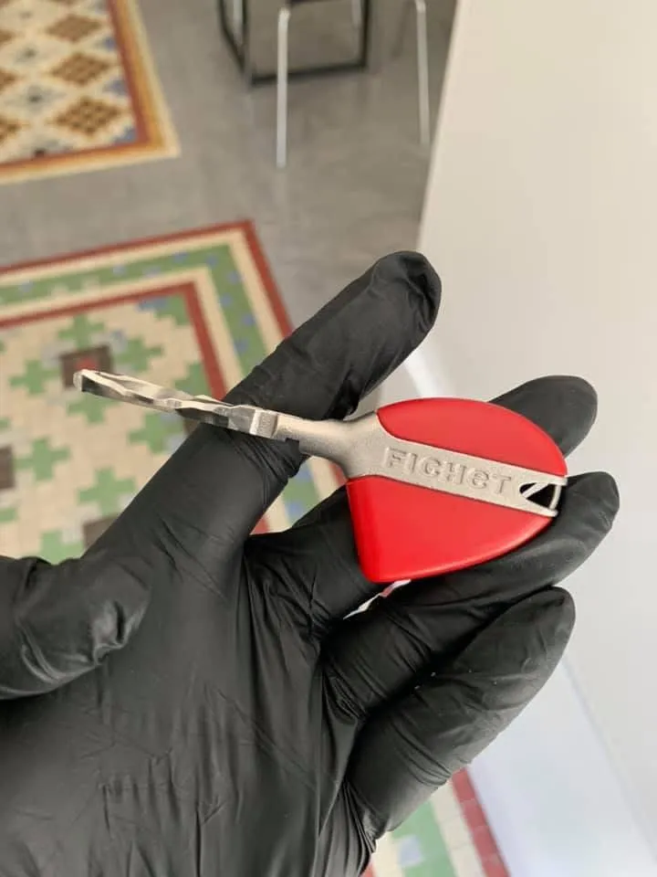 Llave de seguridad Fichet con la cabeza roja, en la mano enguantada de uno de nuestros técnicos en Móstoles.